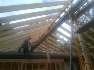 Rafters going up over a new addition with a worker on the wall in Levan