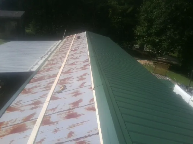 Old rusted panels beside newly installed green metal roofing — Wind Damage Roof Repair by Roofing Brothers in Levan