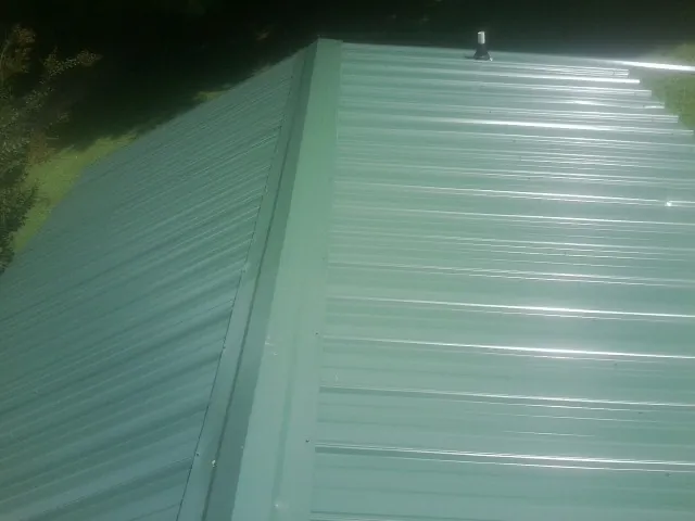 New green metal panels meeting at the ridge of a roof — Flat Roof Repair work by our crew in Levan