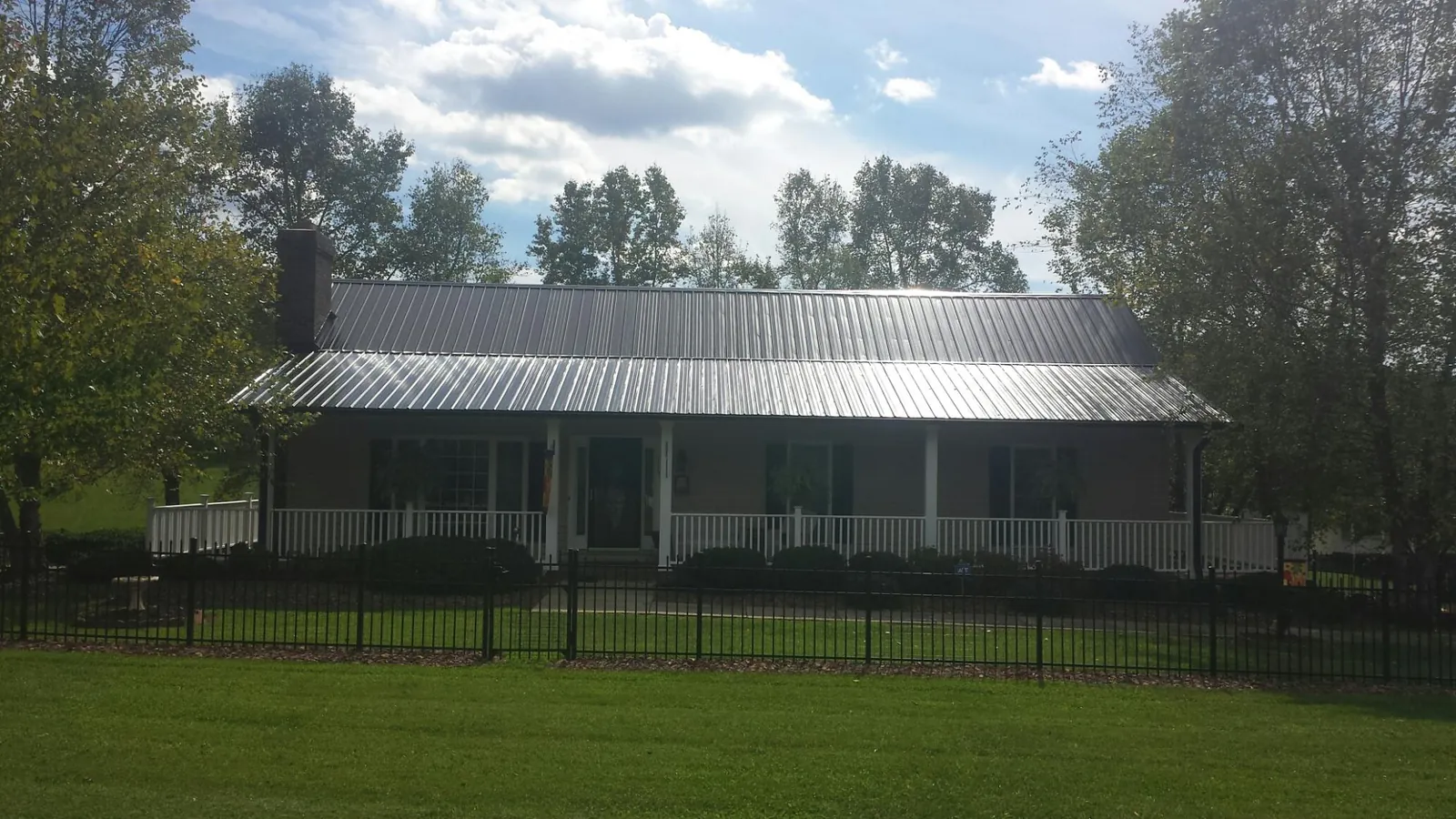 Gray metal roof on a brick ranch with a full width front porch — Gutter Guard Installation work by our crew in Levan
