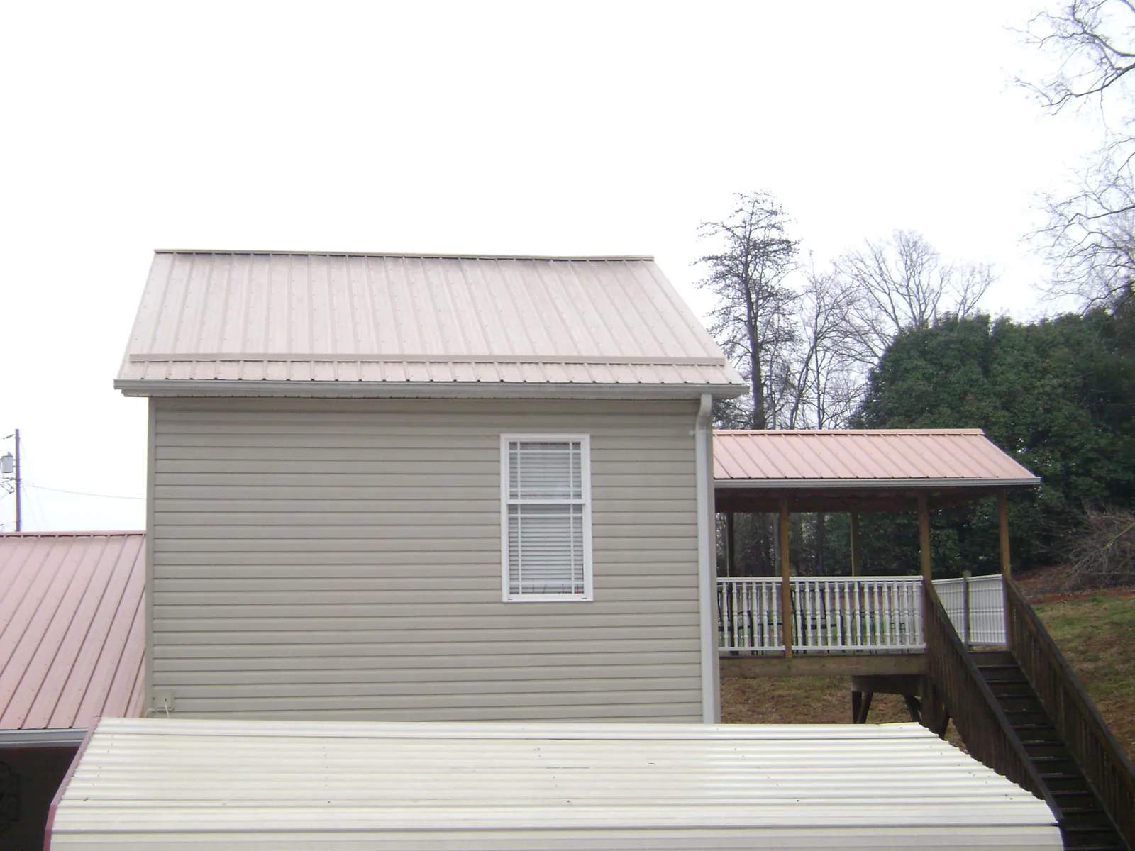 Tan metal roofs on a two story addition and attached porch, from a Roof Replacement job in Levan