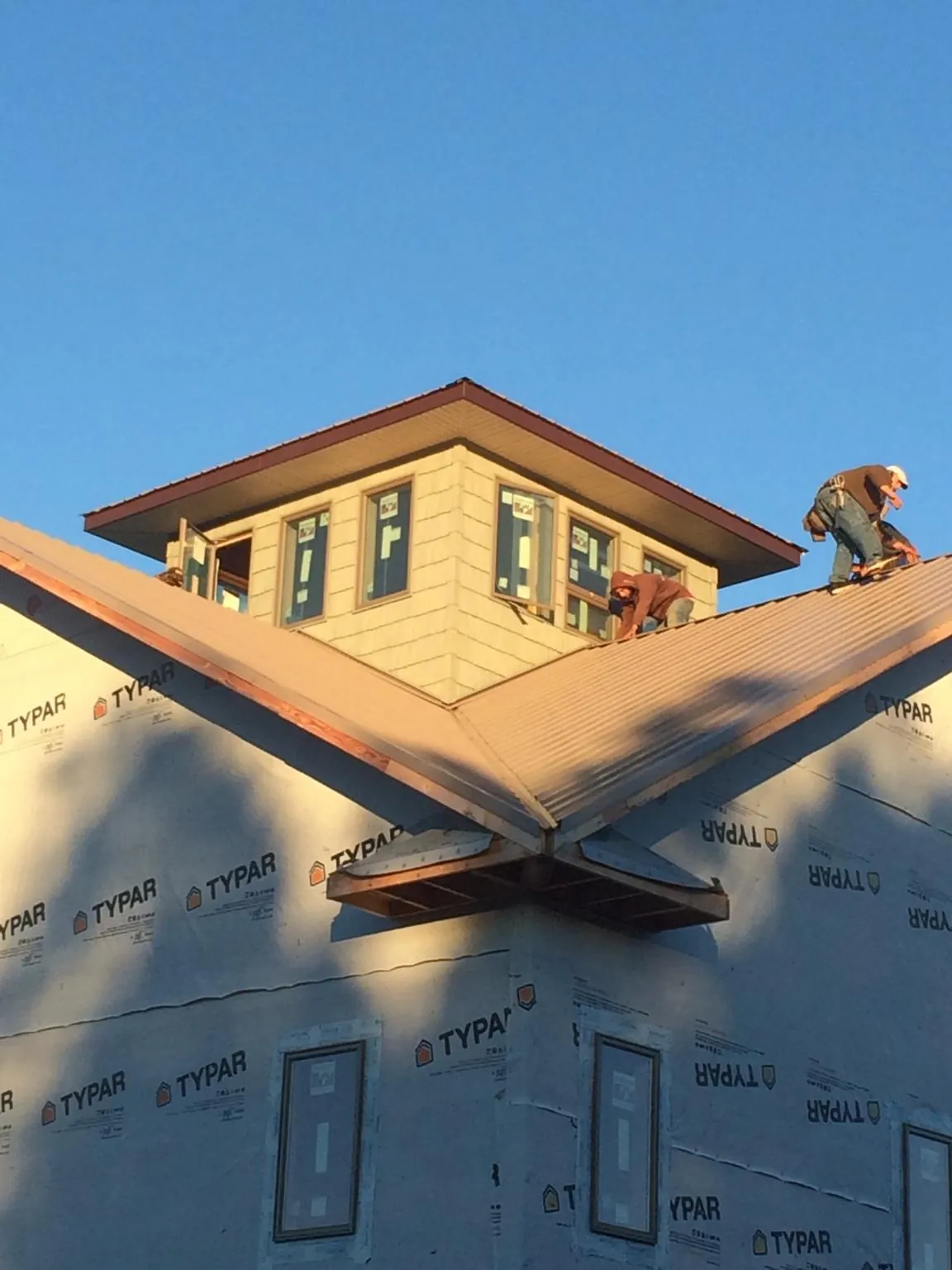 Roofers working around a rooftop cupola on a new metal roof at sunset — Roof Waterproofing in Levan by Roofing Brothers